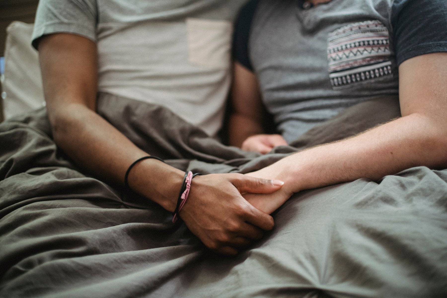 Two Men in Bed Holding Hands